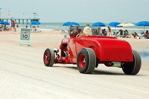 person driving classic car on the beach