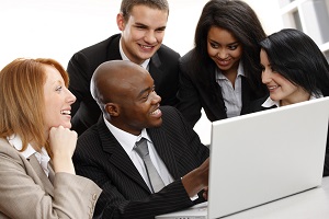 group of business professionals sitting around a laptop talking